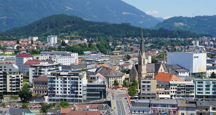 Eine städtische Landschaft einer Stadt mit einer Mischung aus modernen und historischen Gebäuden, umgeben von Bergen.