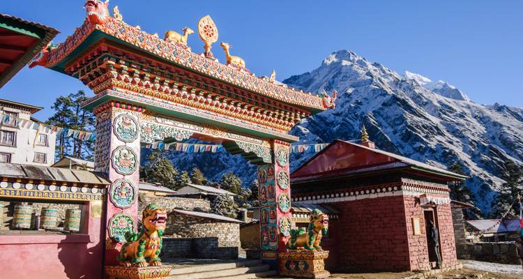 Ein kunstvoll verziertes religiöses Tor mit Bergen im Hintergrund.