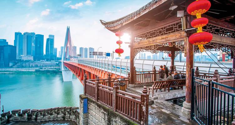 Ein traditioneller chinesischer Pavillon mit Blick auf eine moderne Stadt jenseits eines Flusses.