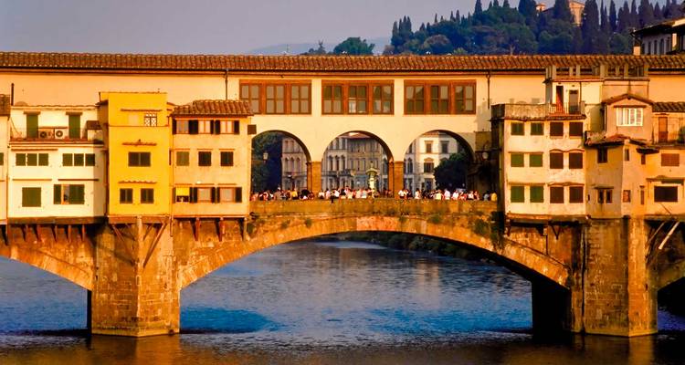 Historic bridge filled with people at sunset.