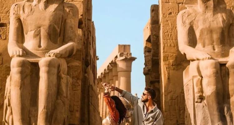 Couple posant entre de grandes statues égyptiennes.
