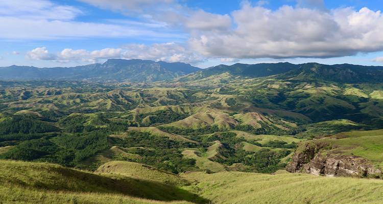 Vue panoramique de magnifiques collines ondulantes sous un ciel bleu avec des nuages.