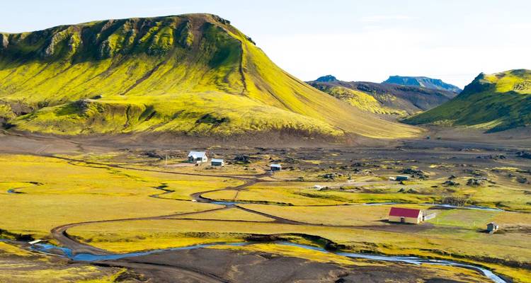 Leuchtend grüne Rhyolit-Bergkämme und verstreute Gehöfte in den abgelegenen Hochlandregionen von Landmannalaugar.