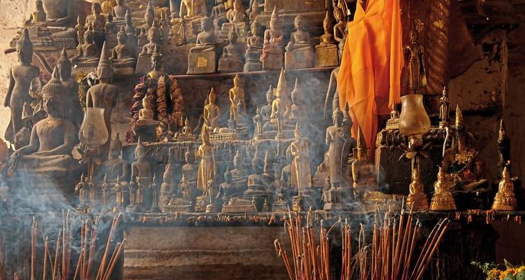 A collection of Buddha statues surrounded by incense smoke.