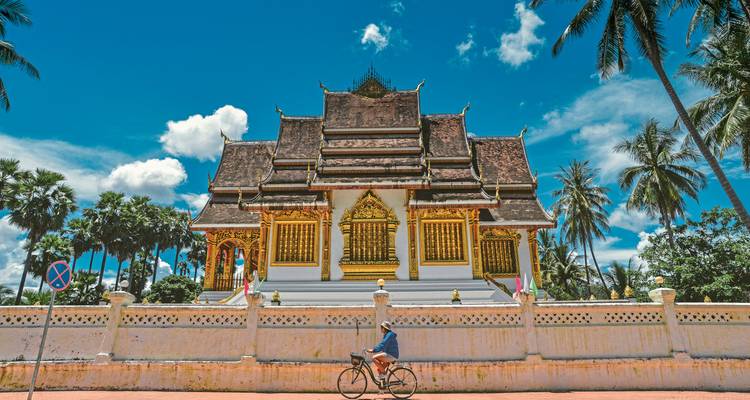 A person biking past a temple with intricate architecture.