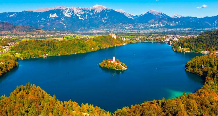 Malerischer See mit einer Insel und Kirche, umgeben von Bergen.
