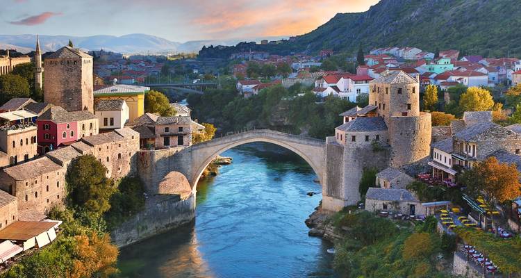 Histórico puente de arco Stari Most que cruza el río Neretva turquesa con pueblo en la ladera