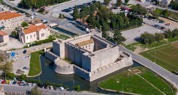 Une vue aérienne d'une forteresse carrée en pierre entourée d'un fossé d'eau près de la côte croate.