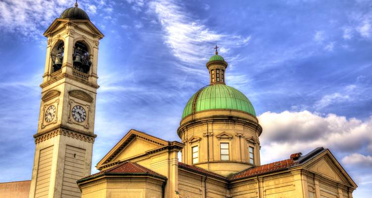 Église avec dôme et clocher contre un ciel dramatique.
