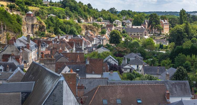 Village de colline avec des bâtiments en brique rouge et en pierre.
