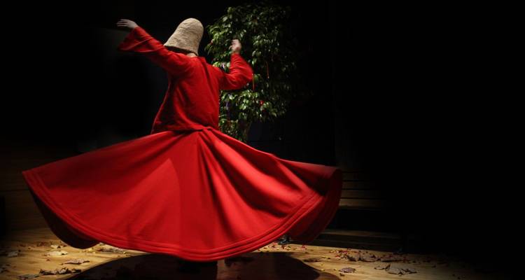Une personne en robe rouge exécutant une danse traditionnelle.