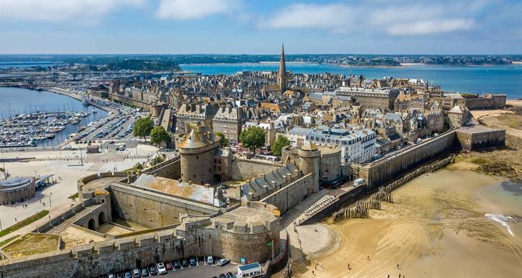 Vue aérienne d'une ville côtière avec des remparts historiques et un port de plaisance.