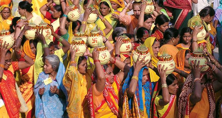 Groep vrouwen in kleurrijke sari's die potten op hun hoofd dragen.