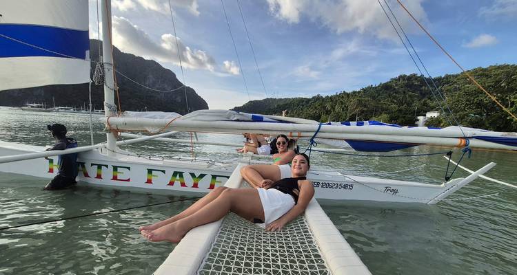 Des gens se détendant sur un catamaran dans des eaux tropicales.