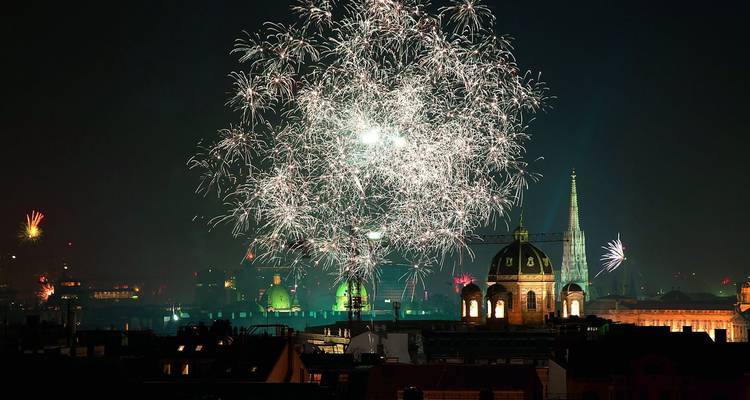 Des feux d'artifice colorés explosent au-dessus de l'horizon de Vienne avec le dôme vert du Musée d'histoire de l'art et la flèche de la cathédrale Saint-Étienne