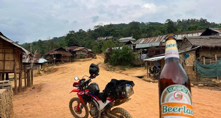 Bouteille de Beerlao et une moto dans un cadre de village rural.
