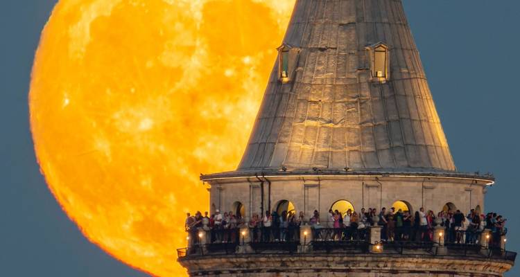 Plateforme d'observation bondée avec un lever de lune géant en arrière-plan.