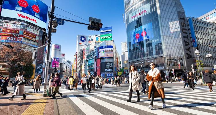 La célèbre intersection de Shibuya à Tokyo, avec ses foules de piétons et ses immenses panneaux publicitaires lumineux partout autour.