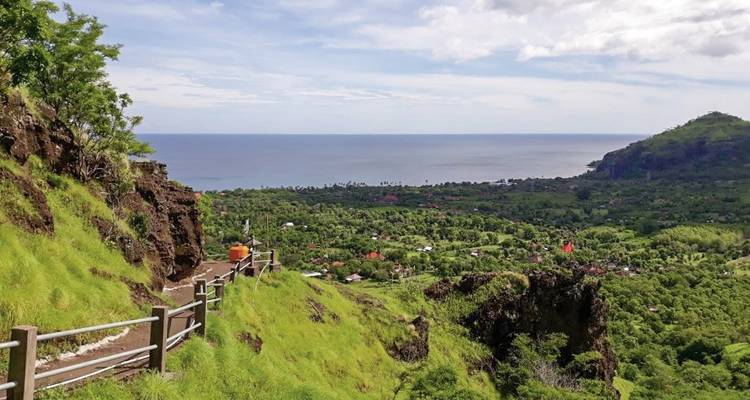 A scenic view of a lush green valley leading to the ocean.
