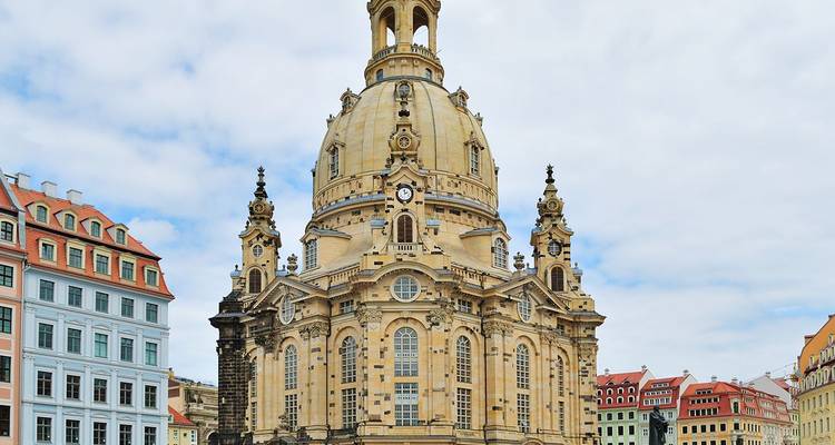 La gran cúpula de piedra y las torres barrocas de la Frauenkirche dominando la plaza Neumarkt de Dresde contra un cielo claro.