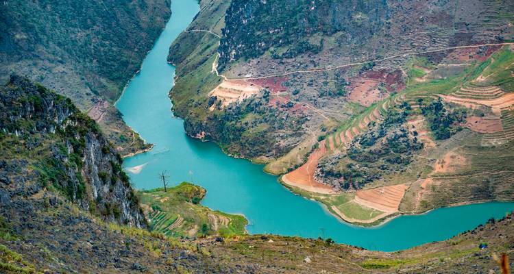 Vista aérea de un río turquesa serpenteante a través de un paisaje accidentado.