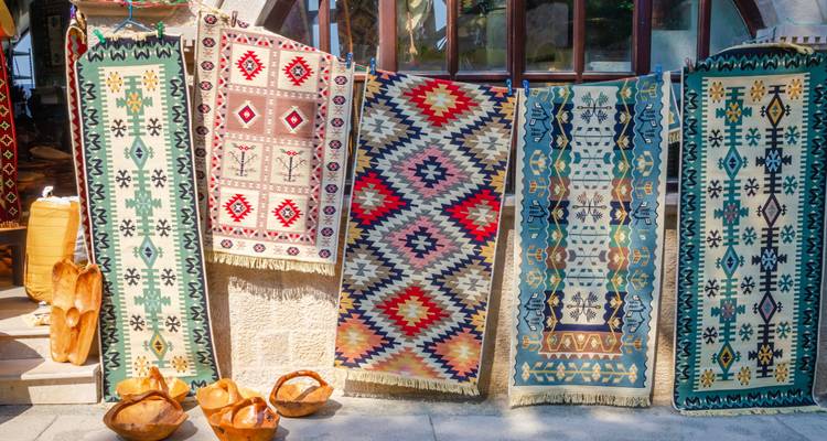 Colorful traditional rugs displayed outdoors.
