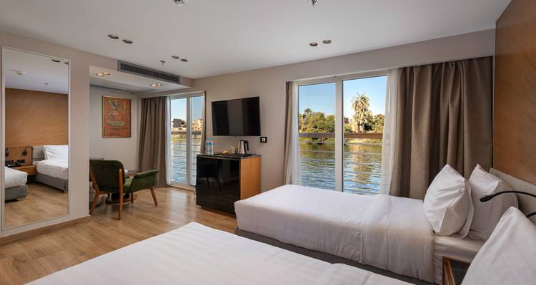 Intérieur d'une chambre d'hôtel avec deux lits et une vue sur une rivière.