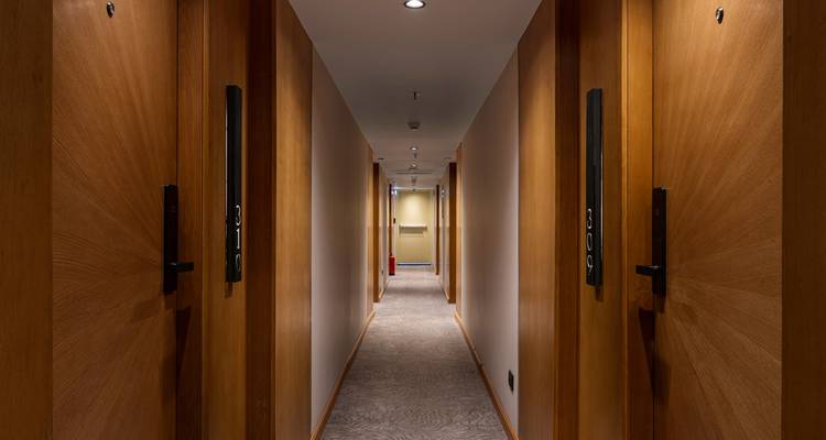 Un couloir d'hôtel avec des portes en bois et un sol moquetté.