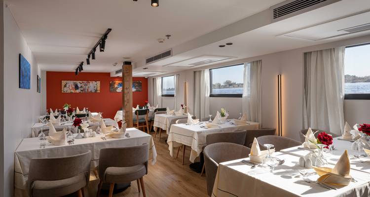 Zone de restauration sur un navire avec des tables soigneusement dressées et vue sur la rivière.