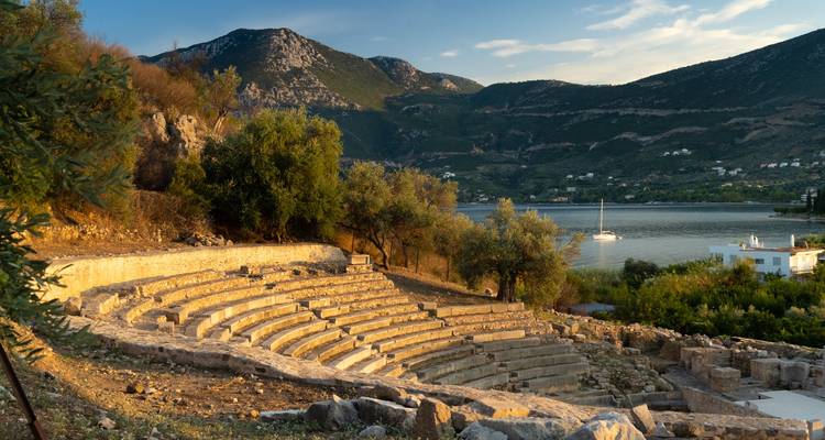 Ancient amphitheater with a scenic lake and mountains in the background.