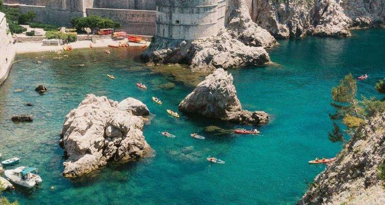 Escena repetida de kayakistas en las aguas cristalinas del Adriático junto a los muros de la fortaleza de Dubrovnik.