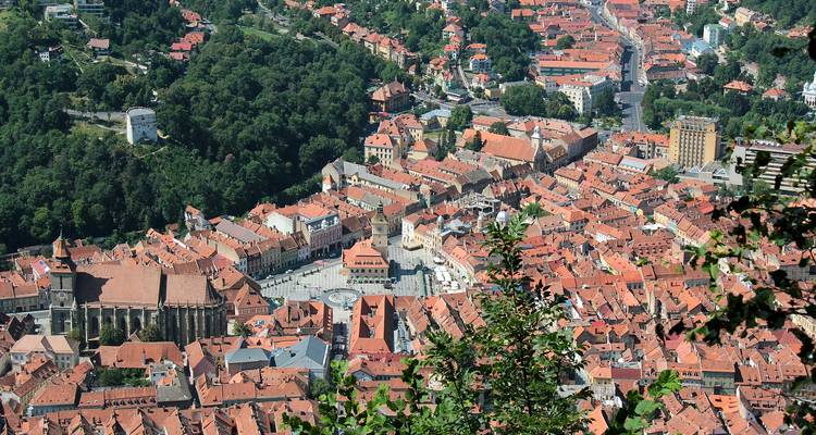 Aerial view of Brasov with red-roofed buildings and central square.