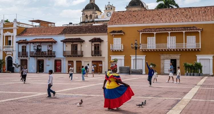 Kleurrijke koloniale gebouwen met mensen die lopen op een plein.