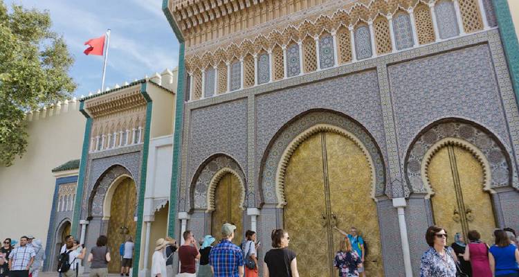 Des touristes devant les portails ornés d'un bâtiment historique.