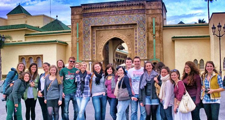 Grand groupe de personnes à l'entrée d'une porte majestueuse.