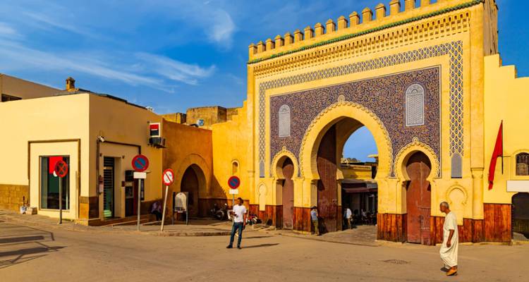 Homme marchant devant la majestueuse porte bleue d'une médina.