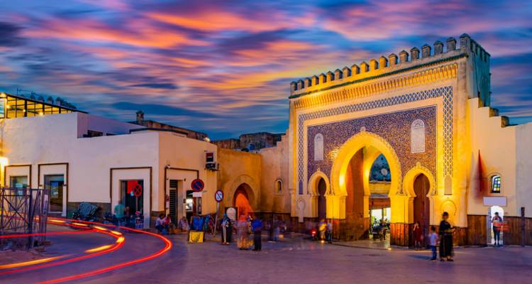 Portail bleu vibrant avec animation de rue au coucher du soleil.