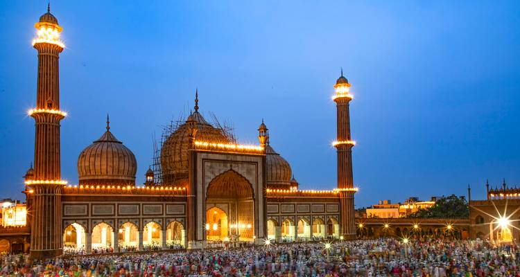 Große Moschee in der Dämmerung mit beleuchteten Kuppeln und Minaretten.