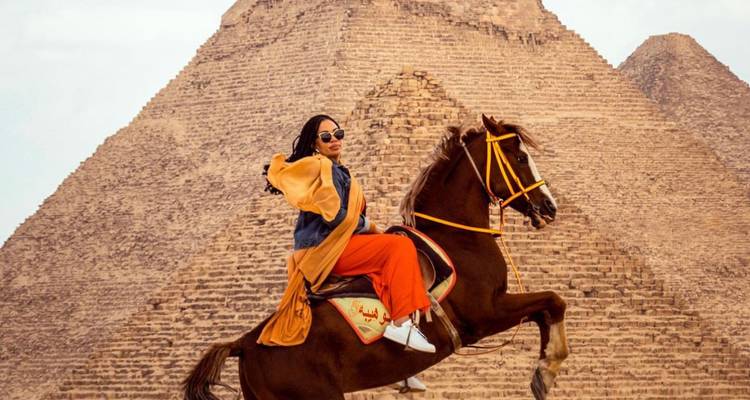 Personne montant à cheval devant une pyramide.