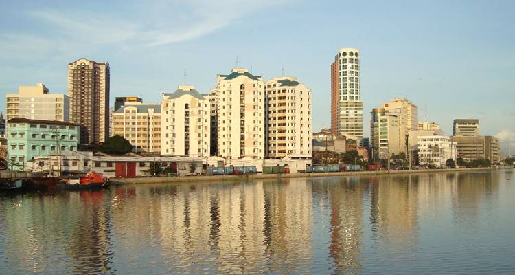 Skyline de Manille avec des gratte-ciel se reflétant dans une rivière calme à la lumière de l'aube