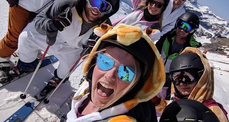 Photo de groupe de skieurs en costumes posant avec enthousiasme sur les pentes enneigées, vêtus de combinaisons animales.