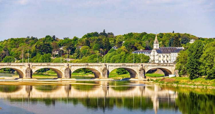 Un pont se reflétant dans une rivière, entouré d'une végétation luxuriante.