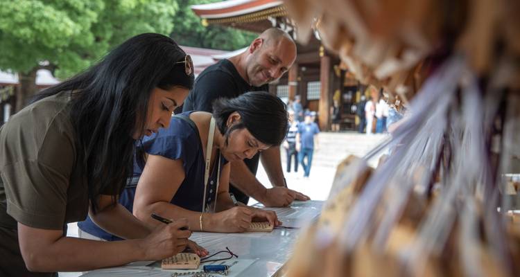 Los viajeros escriben deseos en tablillas de oración de madera en una mesa de santuario sintoísta.