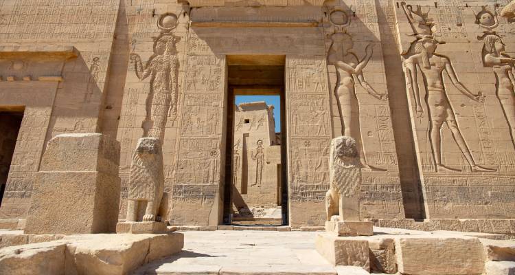Stenen leeuwen bewaken de ingewikkeld uitgesneden ingangsmurenvan de Philae Tempel die in de zon baadt.