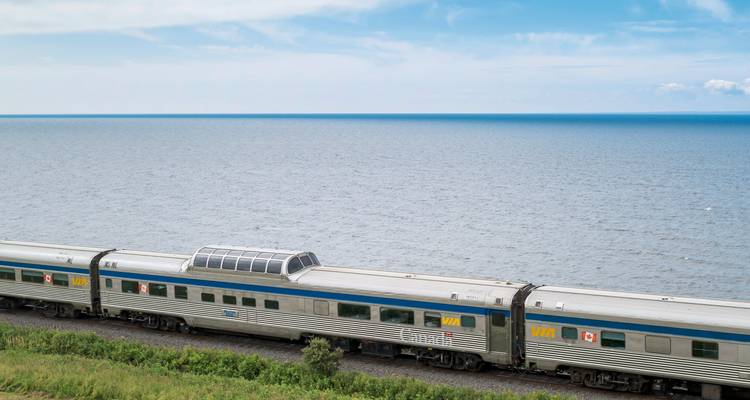 Wagons de train voyageant le long d'une vaste étendue d'eau.