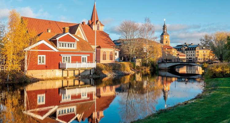 Bunte Häuser entlang eines Flusses mit Spiegelungen.