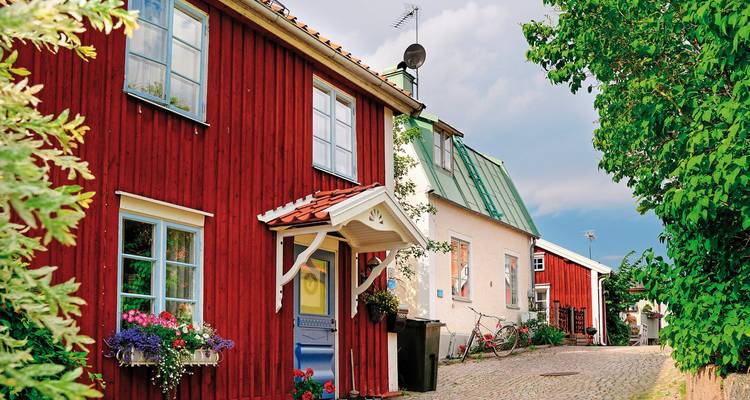 Traditionelle Holzhäuser an Kopfsteinpflasterstraße.