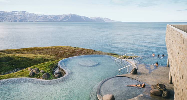 Infinity-Pool mit Blick auf eine malerische Meereslandschaft mit Bergen.