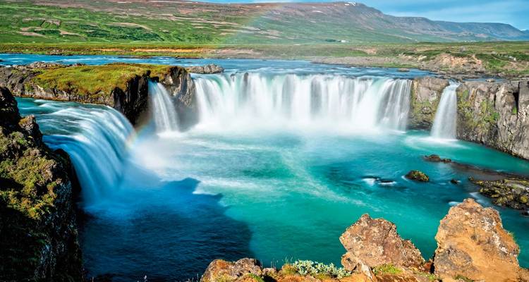 Kraftvoller Wasserfall mit klarem blauen Wasser und Regenbogen.