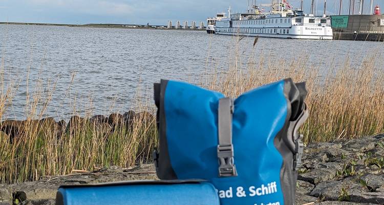 Vélo et sac bleu avec un navire de croisière amarré dans un port.